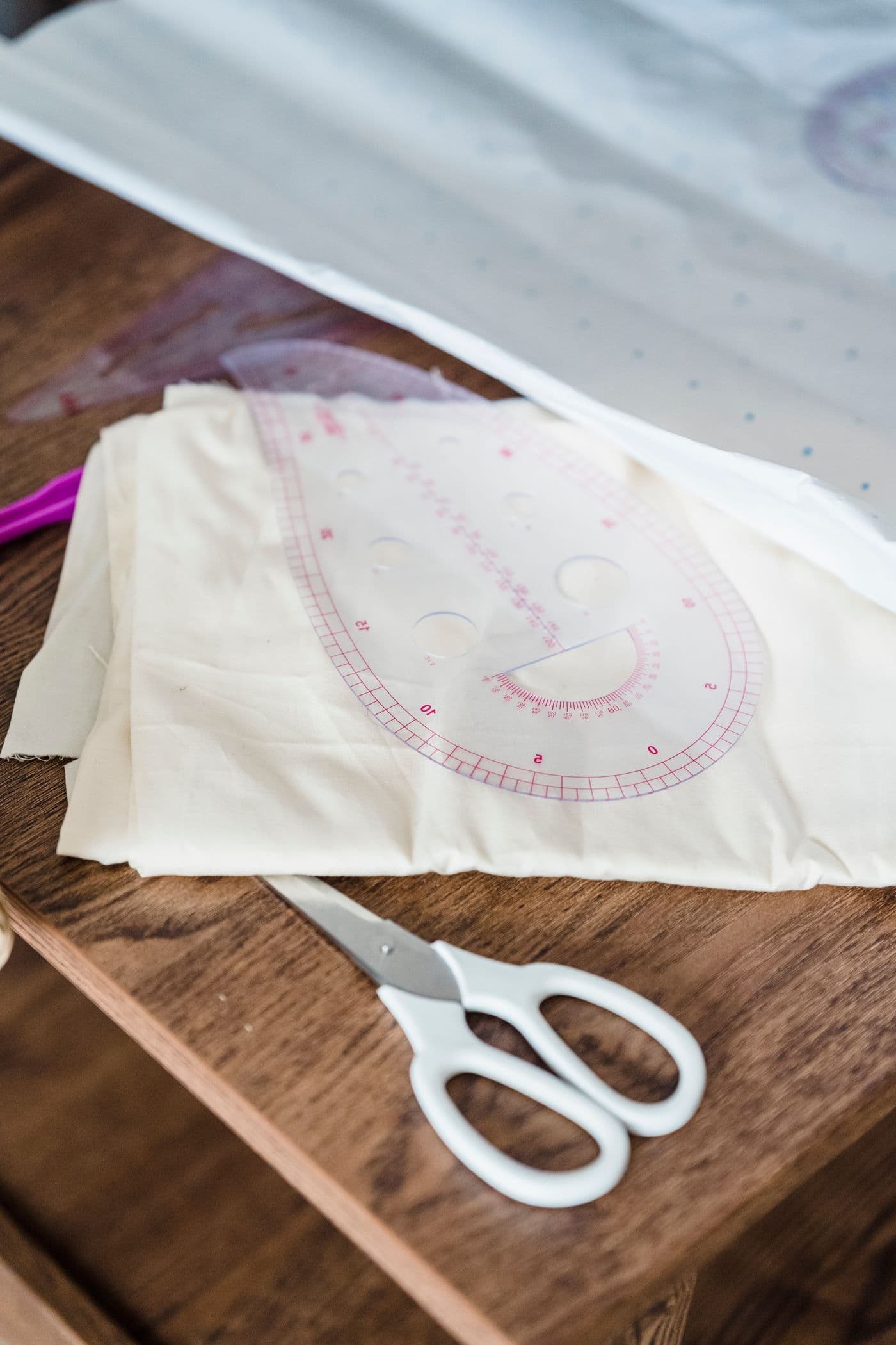Ferramentas de costura sobre papel e tecido em uma mesa de ateliê