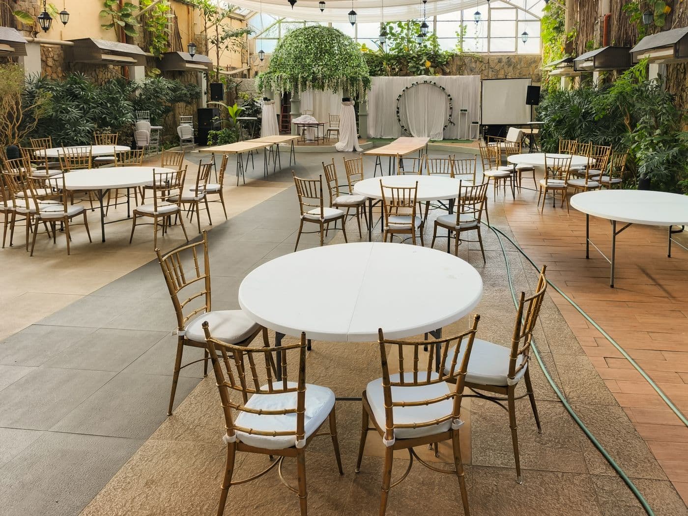 Salón interior preparado con mesas redondas y sillas para un evento.