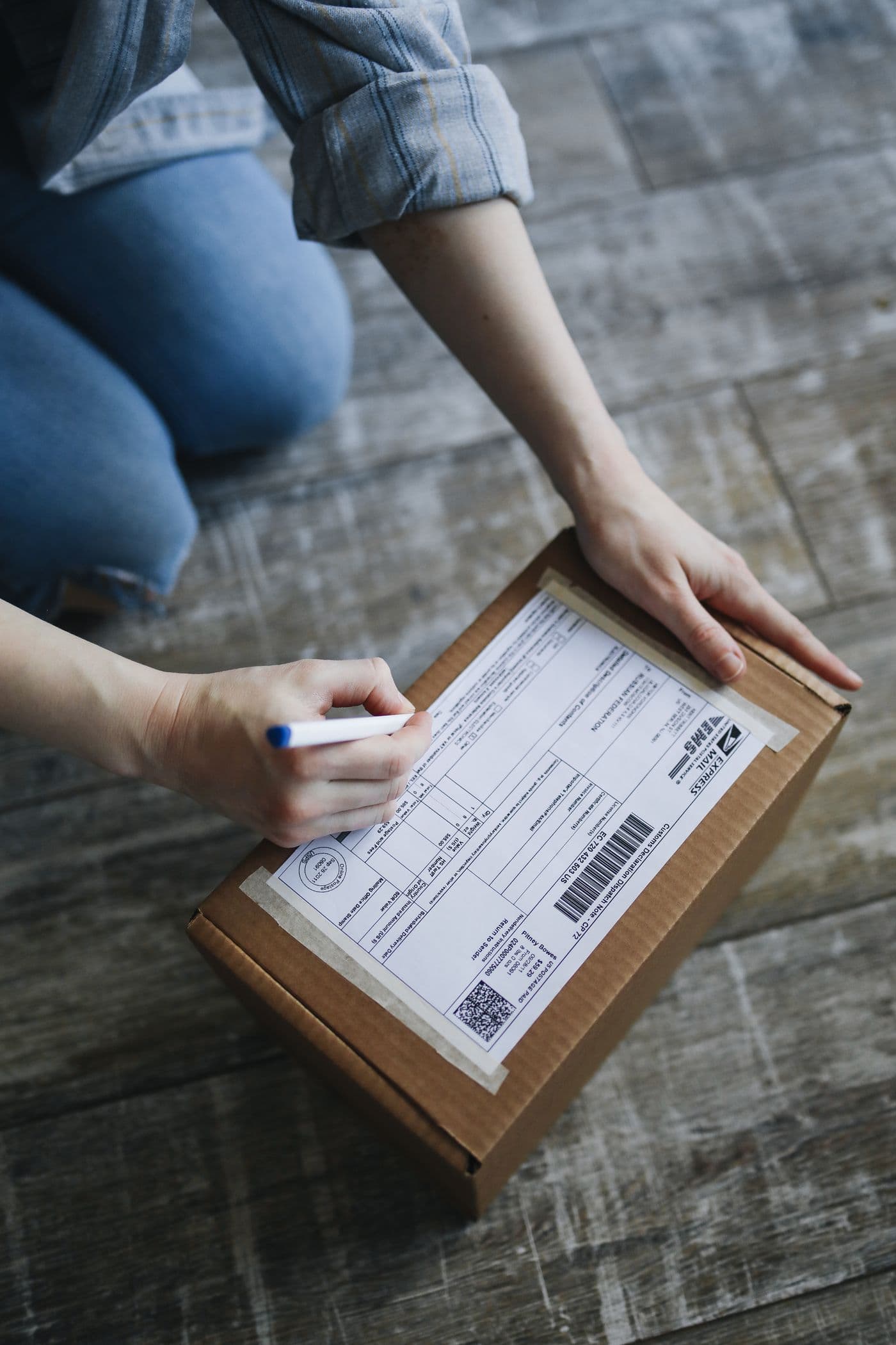 Una persona escribe sobre la etiqueta adherida a una caja de cartón.