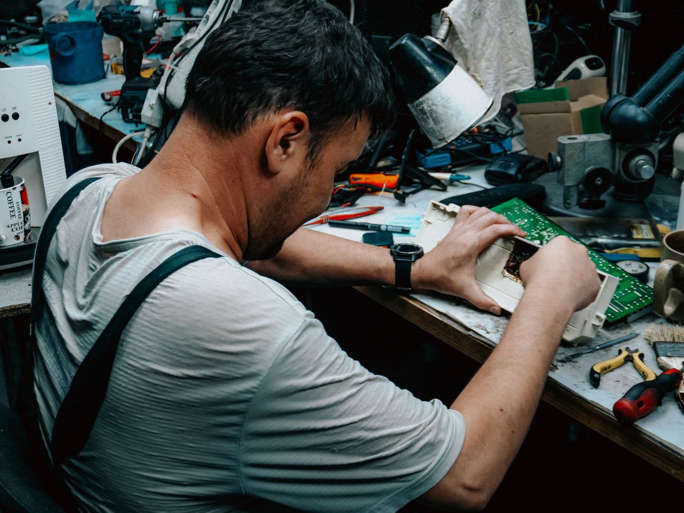 Un técnico trabaja con un aparato abierto y una placa electrónica sobre una mesa de taller.