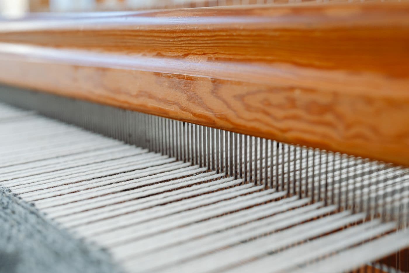 Detalle de hilos tensados y piezas de madera de un telar.