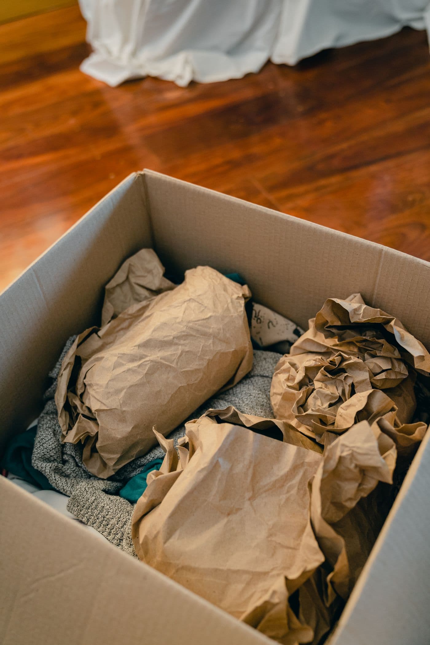 Umzugskarton mit in braunes Papier eingewickelten Gegenständen