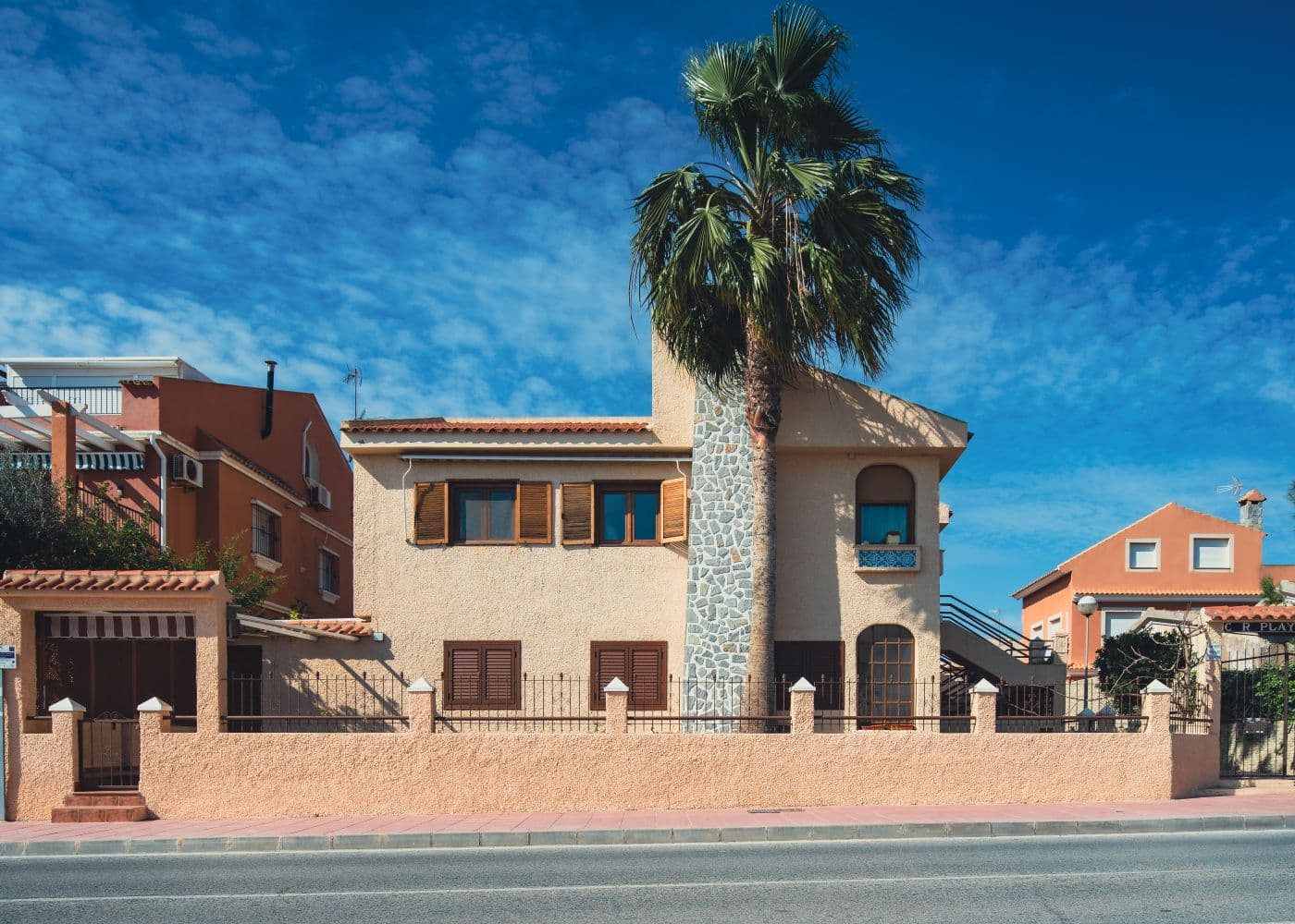 Fachada de una casa rural con una palmera delante.