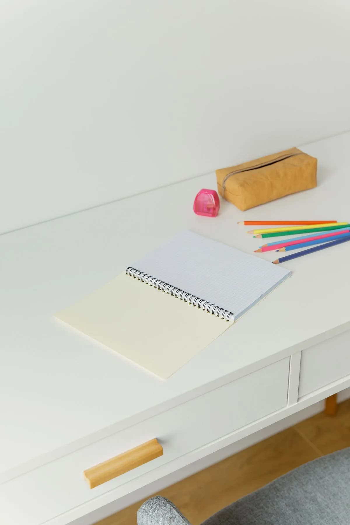 An open notebook and coloured pencils on a white desk